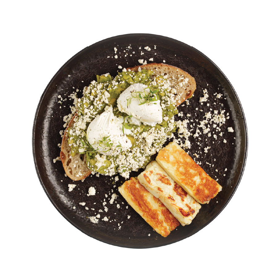 Plated dish with toast, cheese, and green spread on a black plate